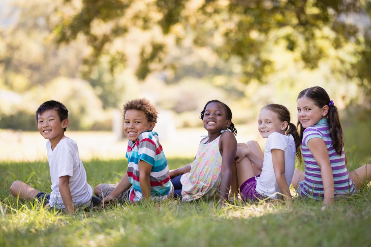 Portrait of smiling friends sitting on grass at campsit